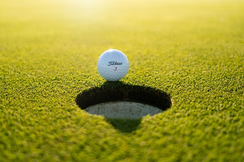 Golf ball teetering on the brink of the hole