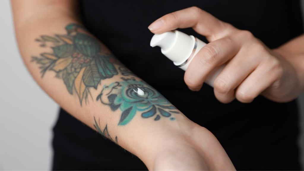 A person applying moisturizer to their tattoo. 