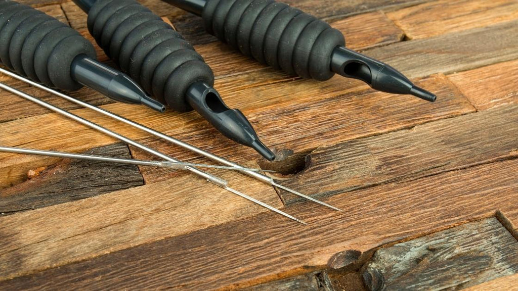 Tattoo guns and needles laying on a table. 