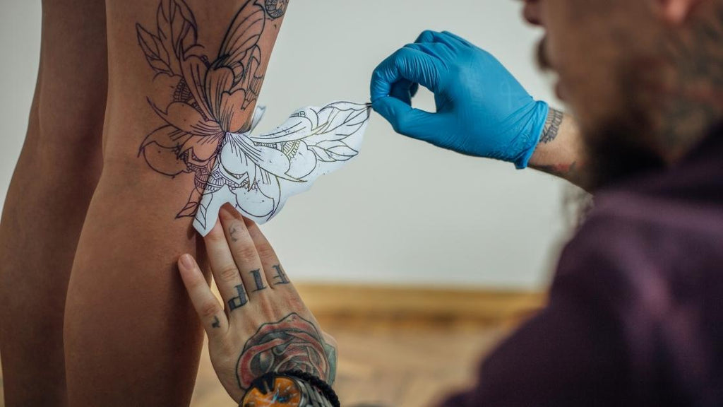A tattoo artist applying a stencil for a tattoo.