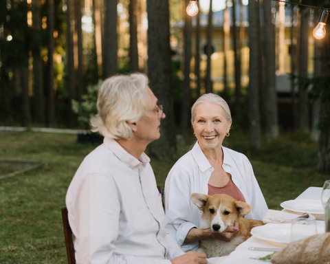 Mature Couple sitting down to eat with their dog