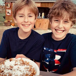 Two Boys Smiling Over a Plate of Funnel Cake