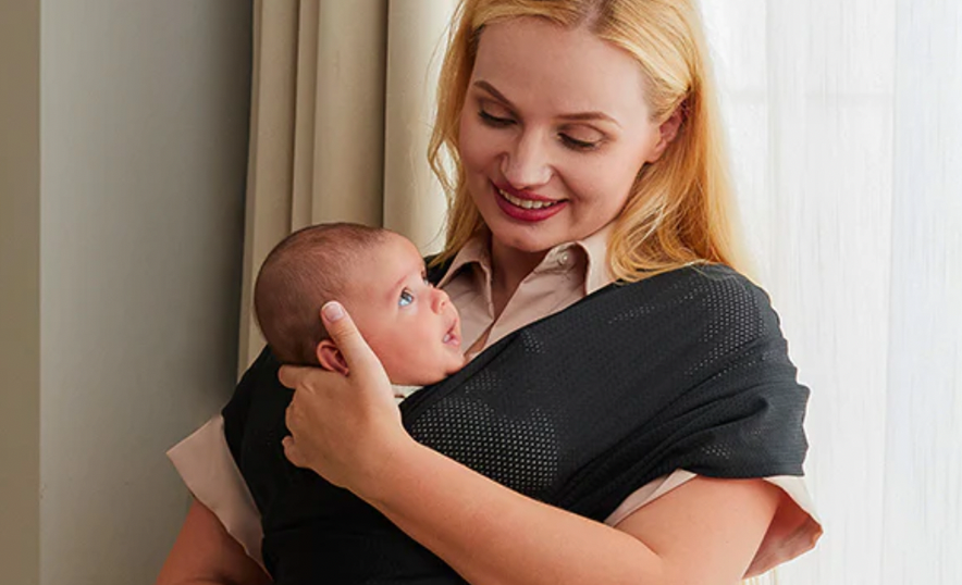 Une maman tient son bébé à proximité avec une enveloppe de bébé.