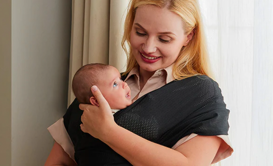 A mom holds her baby close with a baby wrap.