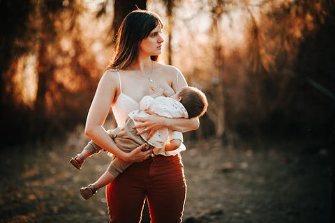 A woman breastfeeds her baby in the forest