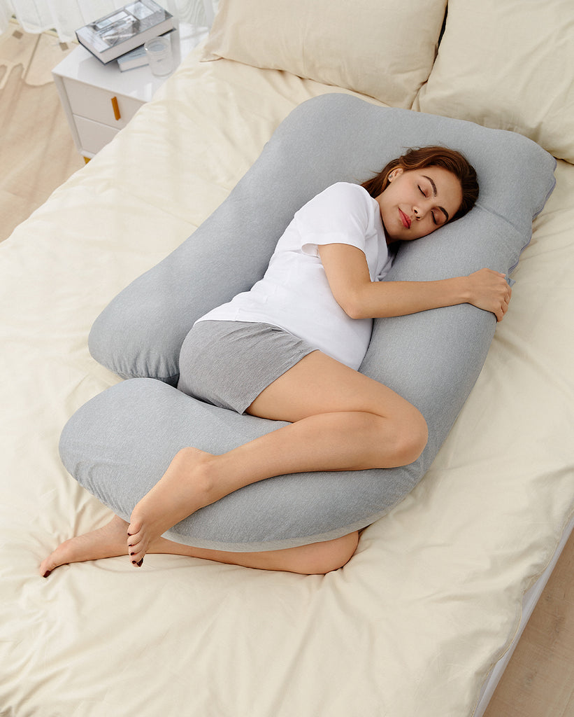 A pregnant mother lying in bed using a maternity nursing pillow