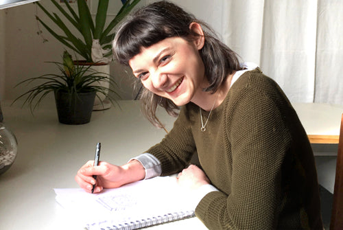 artist Emily May drawing on a desk