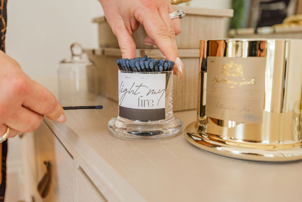 Lighting a match to light a luxury gold candle from Katrina and co