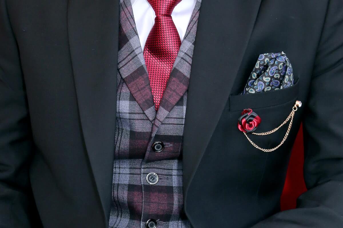Tipuri de costume barbatesti - sacou negru, cravata rosie, vesta in carouri, lant auriu la sacou, batista