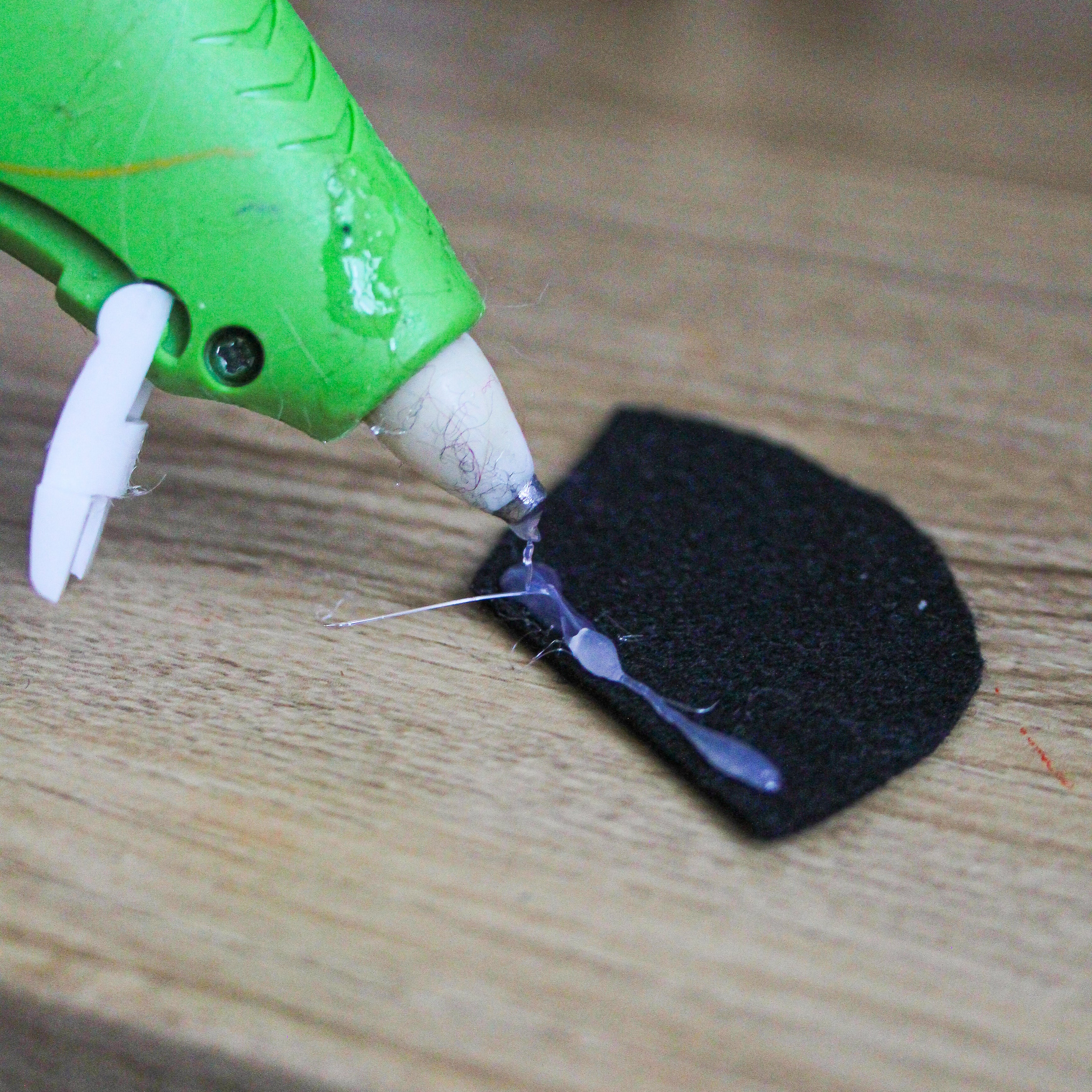 Hot glue is being placed on a felt piece.