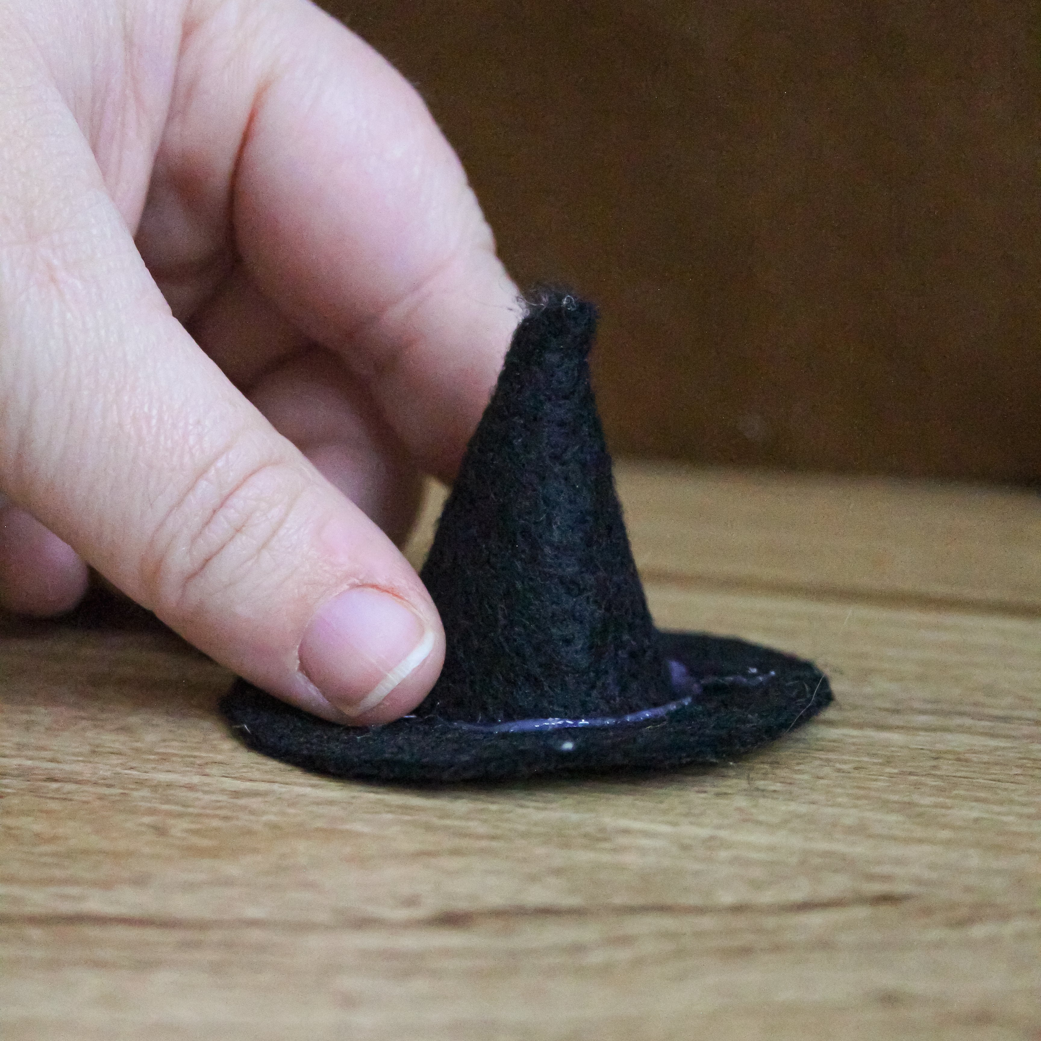A witch hat is being formed through glueing felt.