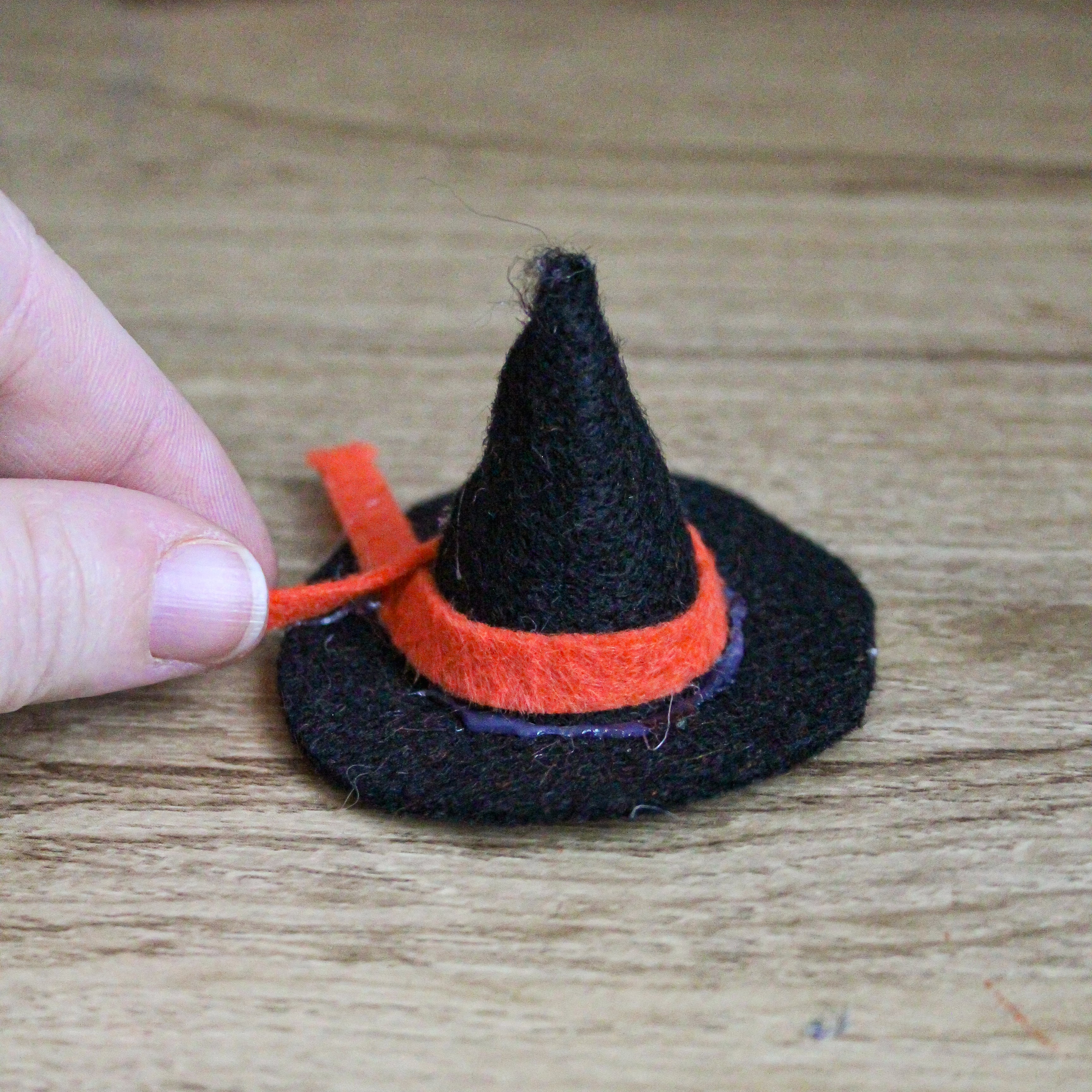 A felt witch hat is being glued together.