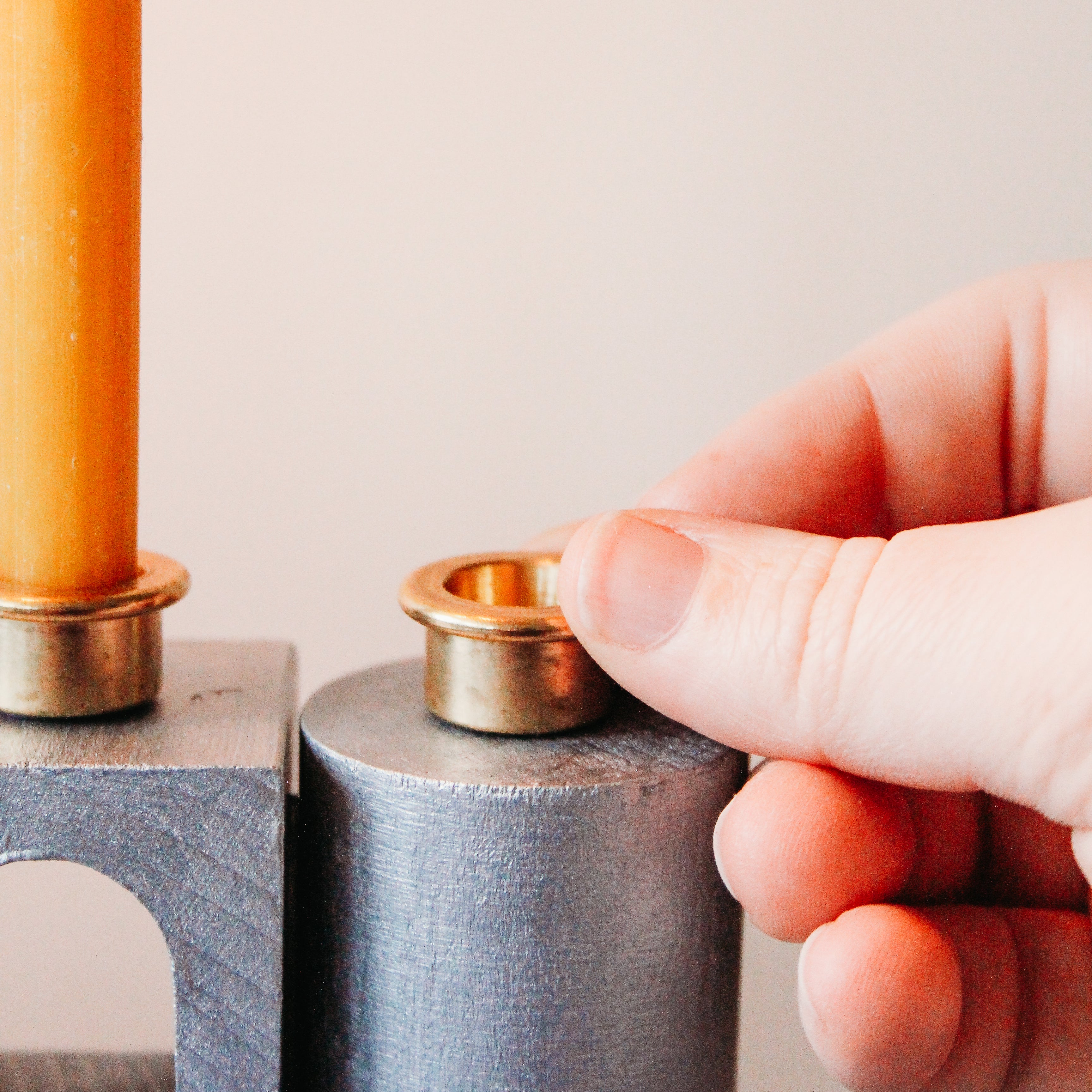A hand is glueing on small brass candleholders.