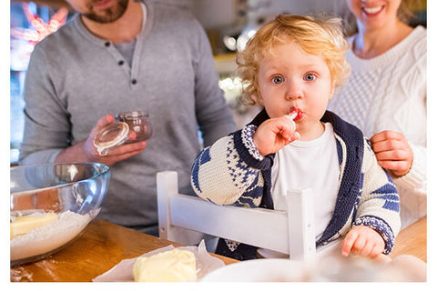 Family cooking, child looking at camera licking batter off finger