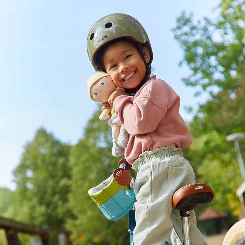 A young girl is going on a bike ride with her doll.