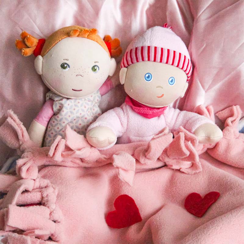 Two HABA soft dolls sit under a DIY blanket.