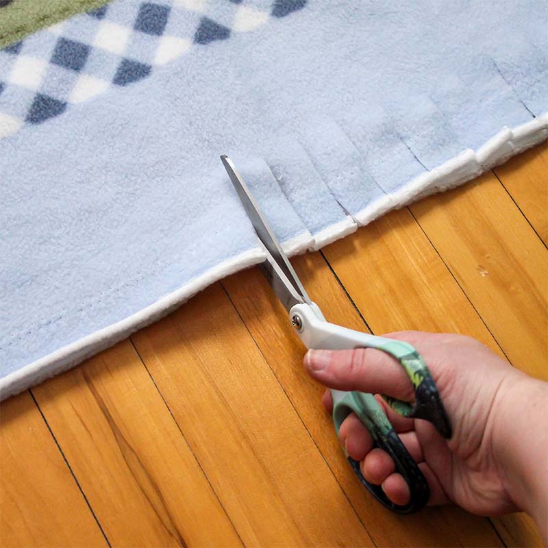Scissors are cutting fleece in strips.