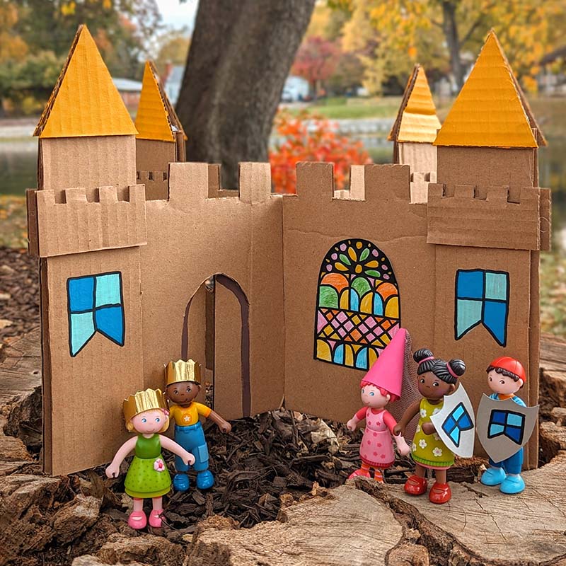 A magical DIY cardboard Little Friends castle sits outside.
