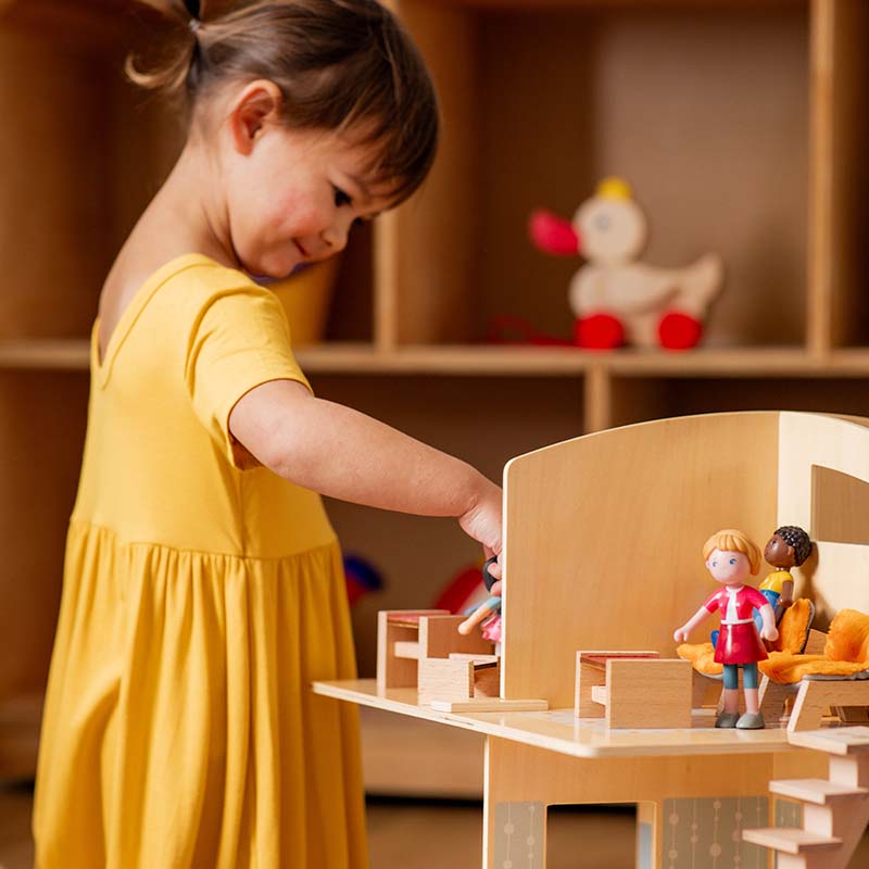 A young girl is playing with HABA Little Friends Dolls.