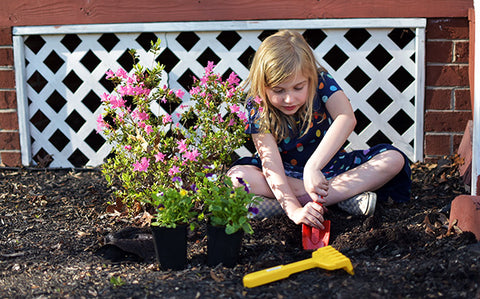 Girl sitting in the dirt digging a garden