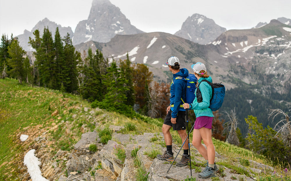 Un ragazzo e una ragazza con bastoncini da trekking contemplano il paesaggio montano