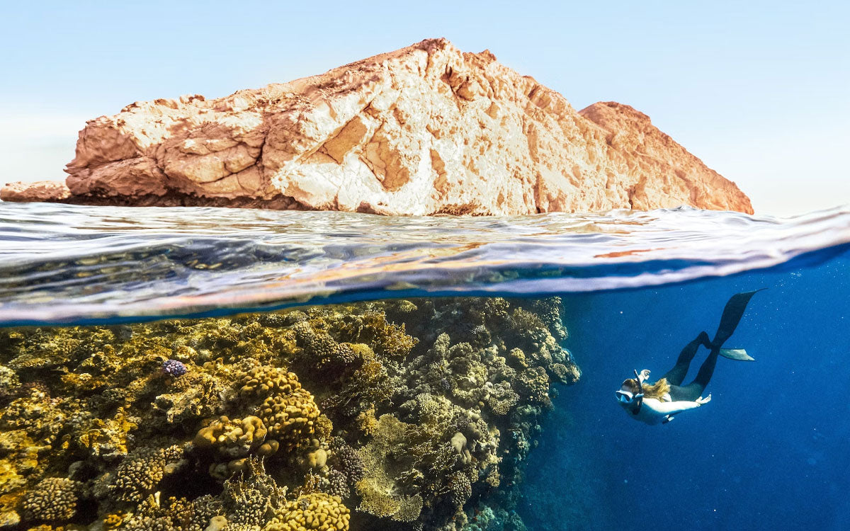 Una ragazza nuota sott'acqua facendo snorkeling