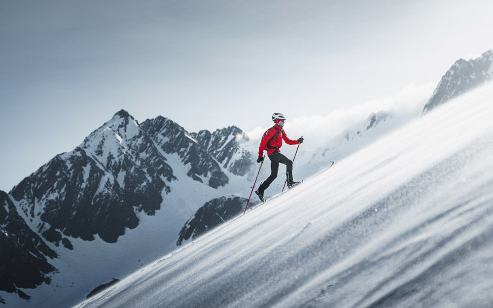 Uno sciatore risale un pendio utilizzando le pelli e l'attrezzatura da scialpinismo
