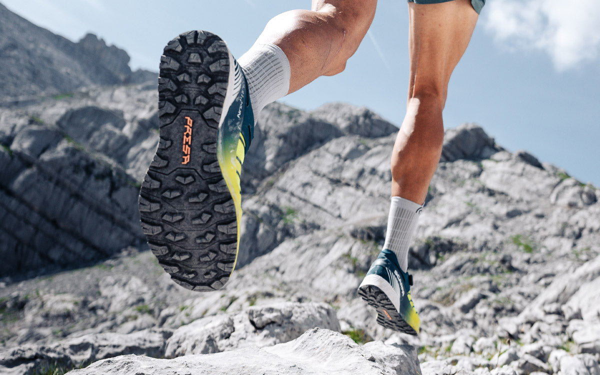 Un ragazzo corre in montagna con le scarpe da trail Scarpa Run Kalibra HT