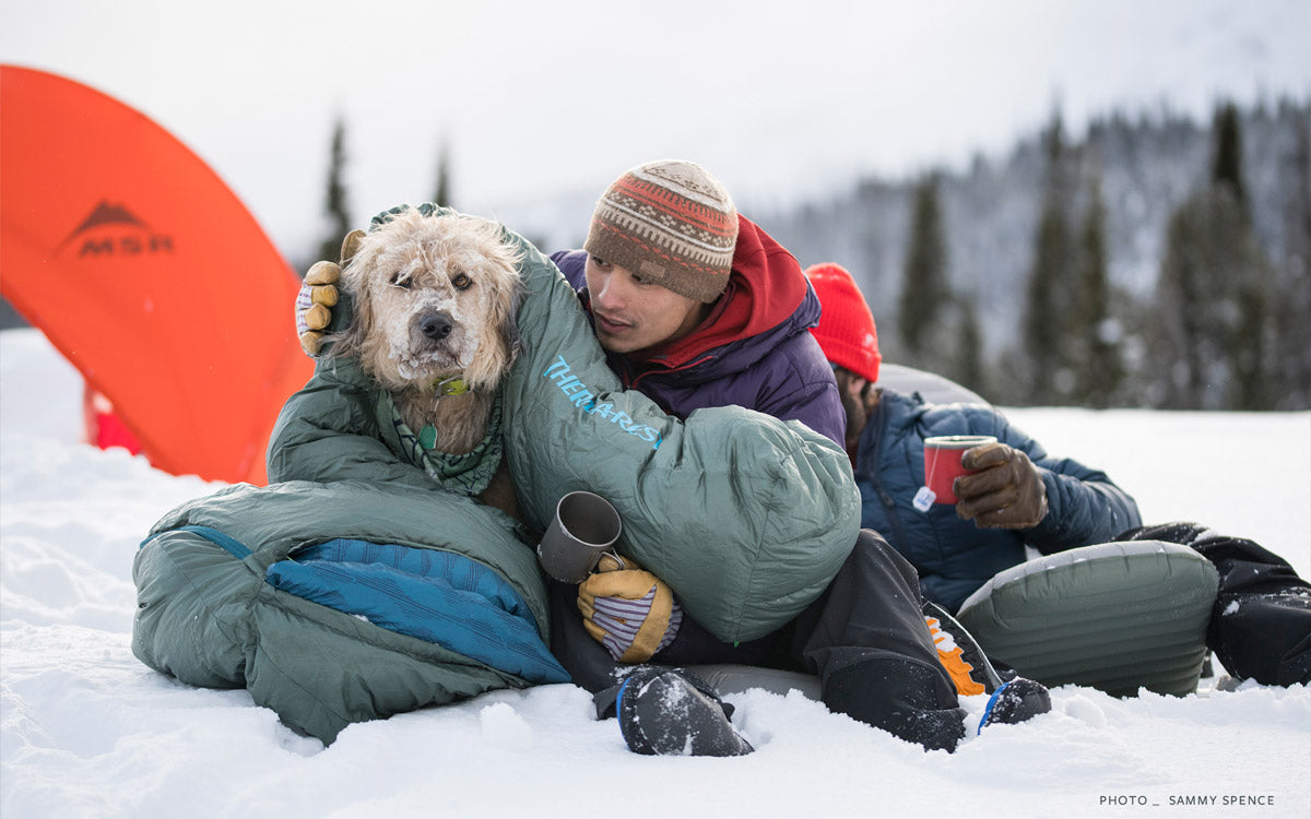 Bivacco invernale, un ragazzo copre il suo cane con un sacco a pelo Therm-a-Rest Questar™