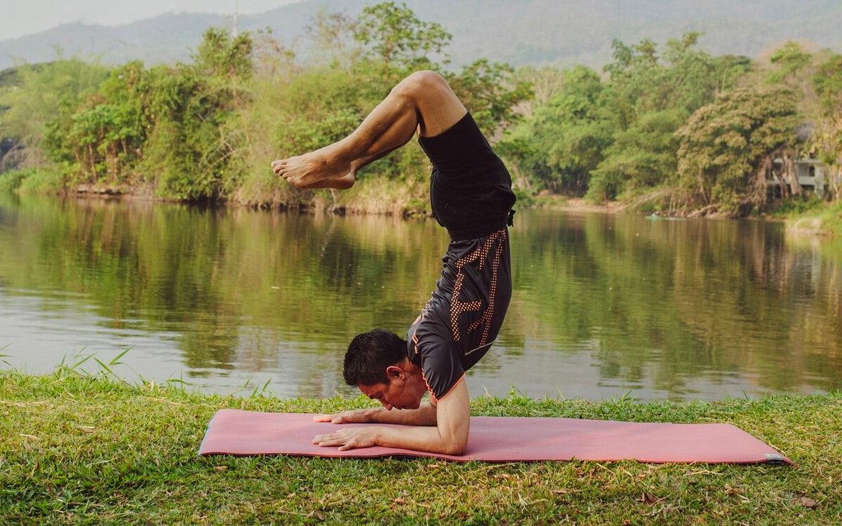 Un ragazzo mantiene una posizione di Yoga sulle rive di un fiume