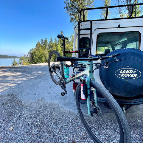 Flat bar gravel bike giant revolt suspended from Altangle hangar connect bike work stand which is attached to a classic land rover overlooking whitefish lake