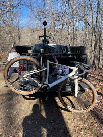 Lauf Seigla Weekend Warrior Wireless being assembled at a trailhead using the Altangle Hangar Connect bicycle work stand for travel and on the go maintenance. The mount anywhere bike stand is attached to a for raptor truck while a gravel bike is attached to the other side of the bike repair stand