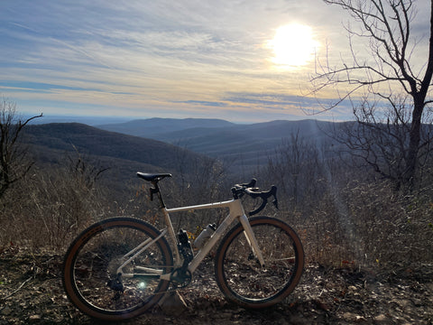 Lauf Seigla Weekend Warrior Wireless gravel bike standing alone with mountains and sunset in background. Gravel bike equipped with Maxxis Ikon 2.2 tan wall tires