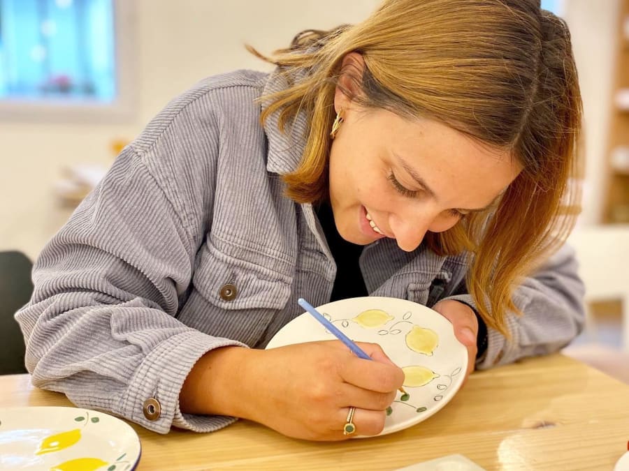 femme qui dessine avec un pinceau sur une assiette en céramique