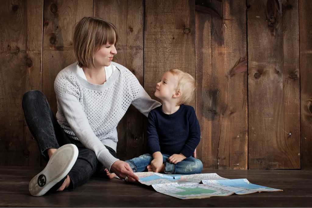 mère et son fils de 5 ans assis devant une carte et un mur en bois foncé