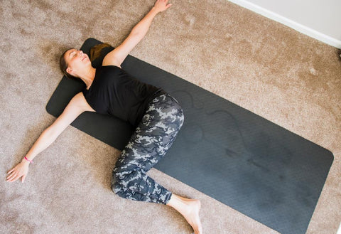 laying on yoga mat with both knees to one side