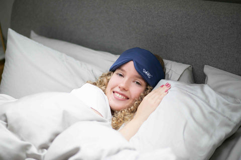 woman in bed with blue sleep mask on