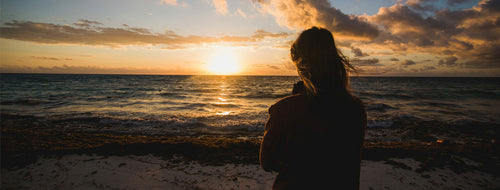 woman looking out to sea at a sunrise