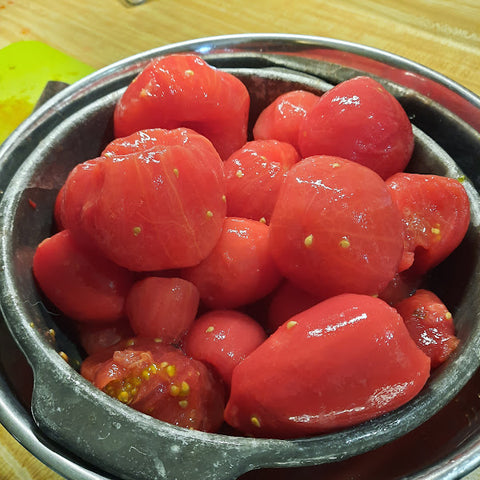 Peeled and cored tomatoes in a strainer