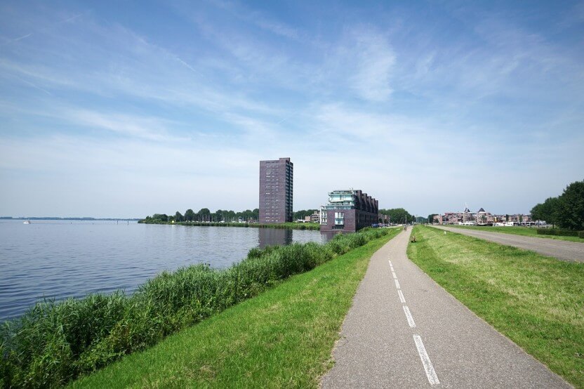 De stad Almere met in de verte Almere haven, woningen en een woontoren.