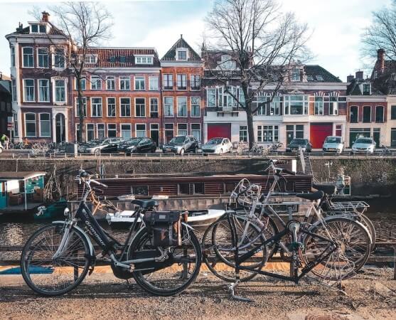 Gracht in Groningen op een winterse dag, met aan weerzijden een weg, woonhuizen en geparkeerde fietsen en auto’s. In de gracht liggen woonboten.