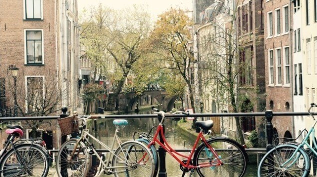 De binnenstad van Utrecht met een gracht, woningen en geparkeerde fietsen tegen de reling van een brug.