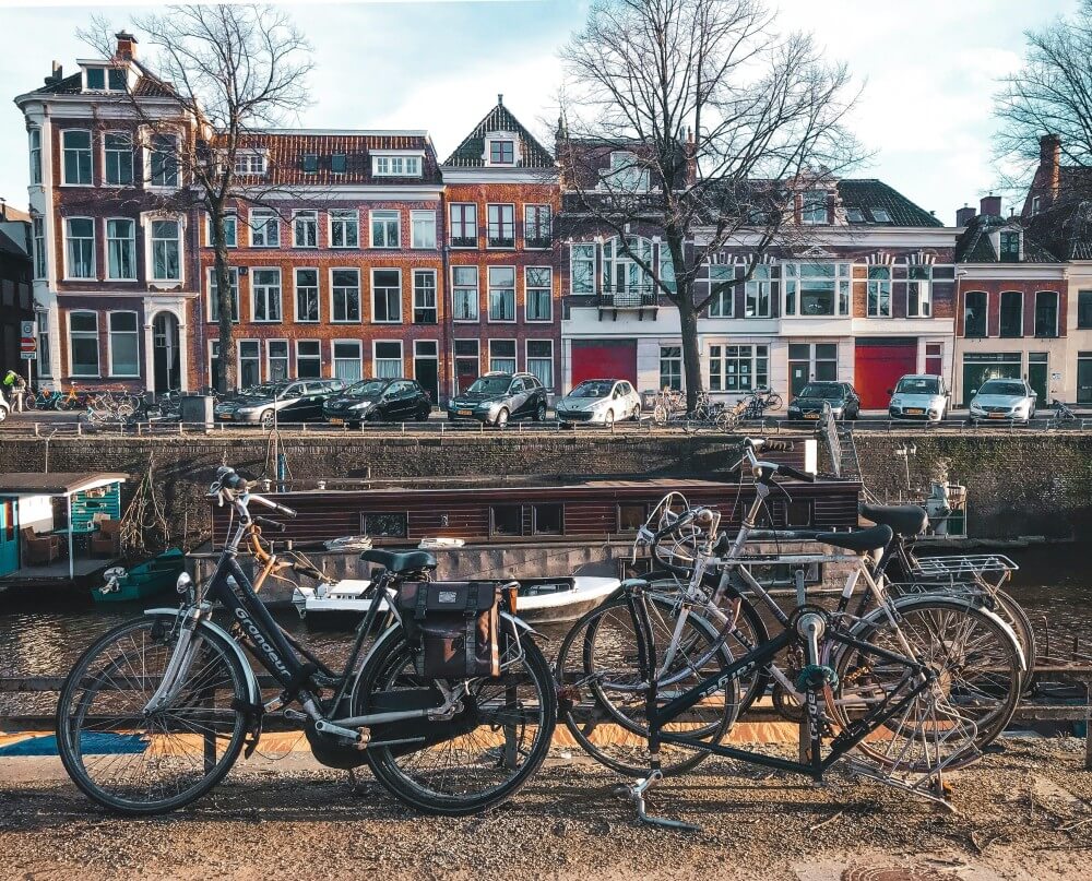 Gracht in Groningen op een winterse dag, met aan weerzijden een weg, woonhuizen en geparkeerde fietsen en auto’s. In de gracht liggen woonboten.