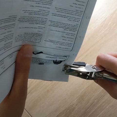 Punching a piece of paper with a single hole punch. 