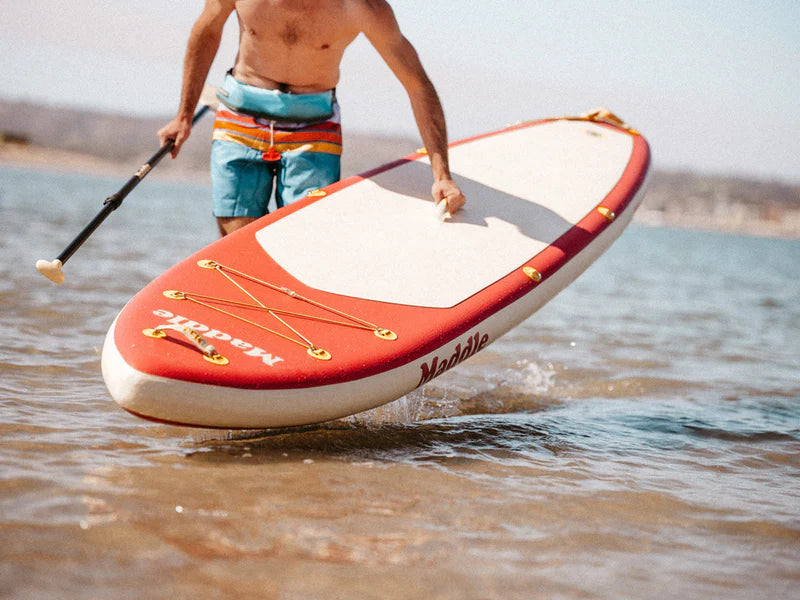 man carrying a stand up paddle board in the water