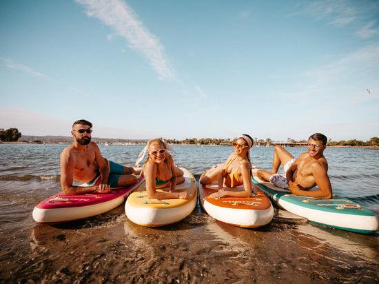 four friends on their paddleboards by the beach