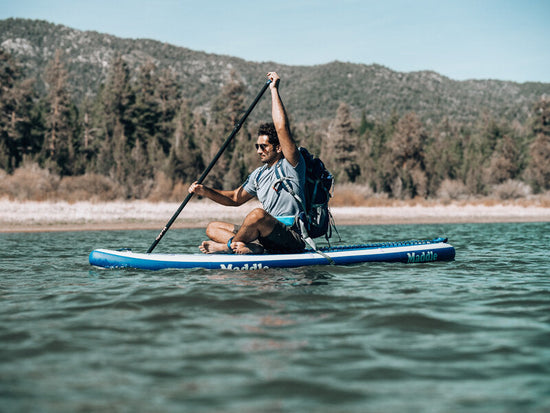 man sitting cross-legged on paddle board