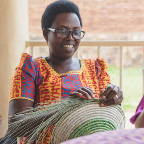 Ruandische Kunsthandwerkerin, die von Hand eine natürliche Korbwarenschale webt
