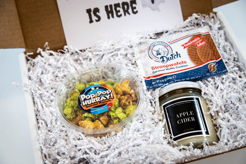 gift box with Spooky Season is Here notecard, stroopwafels, apple cider candle, and caramel apple popcorn surrounded by white crinkle paper (close up)