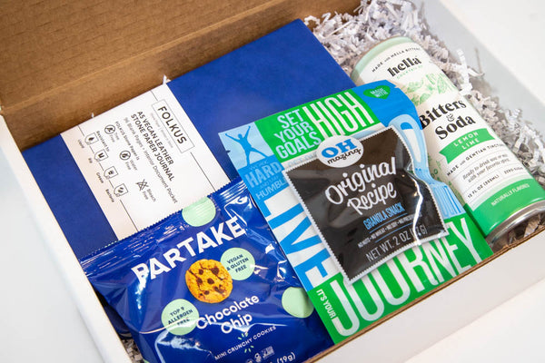 photo of gift box with notebook, cookies, granola and bitters & soda drink